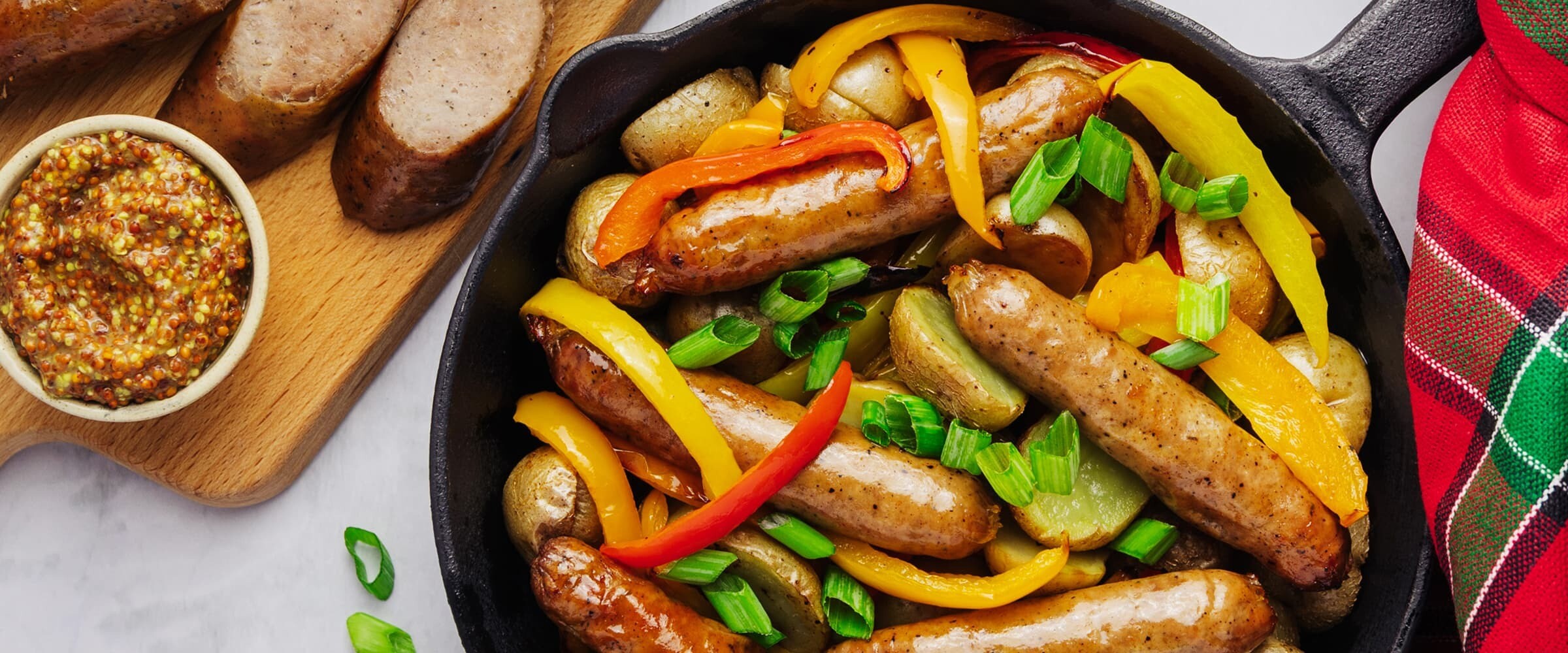 A close-up of sausages, peppers and potatoes in a skillet.