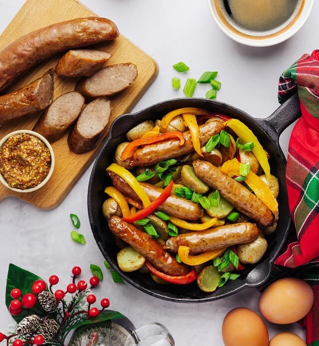 A close-up of sausages, peppers and potatoes in a skillet.