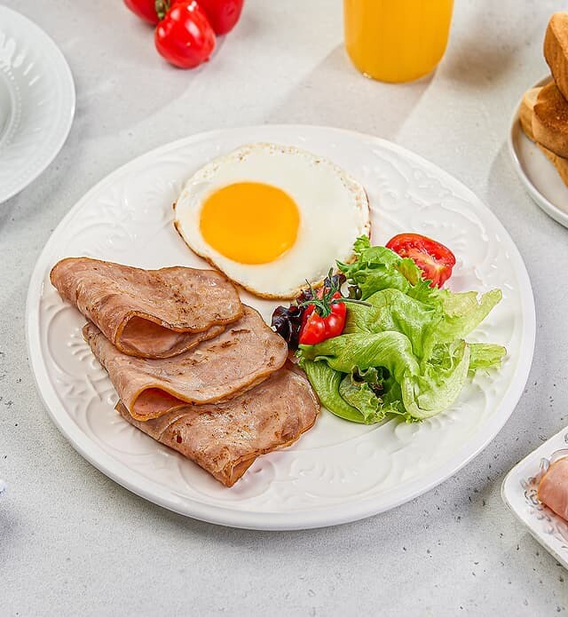 Close-up of a plate of turkey slices, eggs and a salad.
