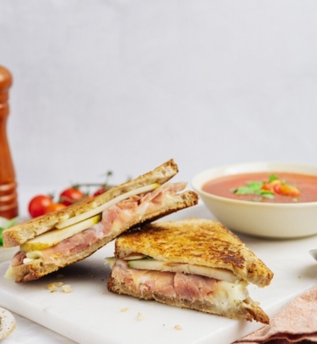 Close-up of a sandwich filled with sliced meat and vegetables.